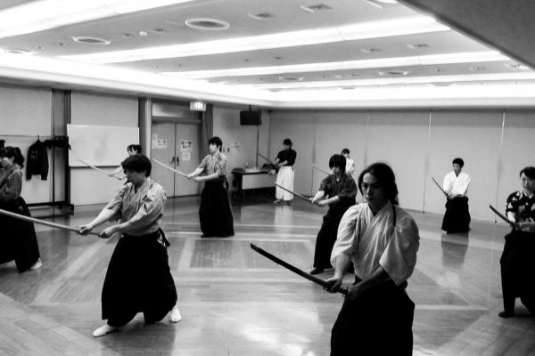 People in traditional Japanese clothes, holding katana swords