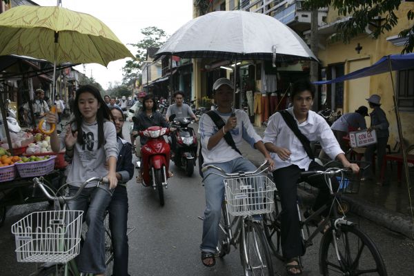 People riding bicycles whilst holding umbrellas